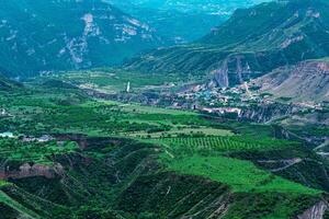 brumoso alpino Valle con pueblo y campos Entre montaña picos foto