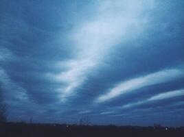 Incredibly bright evening blue sky with long clouds stretching across the sky photo