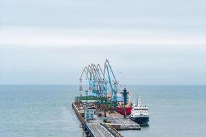 carga atracar con Puerto grúas y amarrado buques en contra el fondo de el abierto mar foto