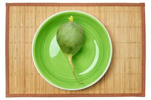 big green radish on a green plate on a cane serving mat photo