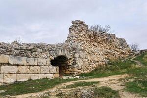 destroyed antique fortress wall with arch and masonry from different centuries photo