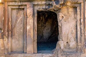 entrance to an ancient stone tomb carved into the rock photo