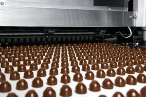 chocolate toppings on the conveyor of a confectionery factory close-up photo