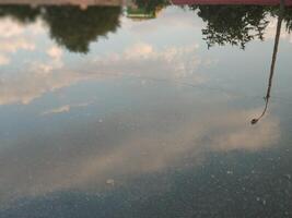 reflexión de el cielo y nubes en un charco en el asfalto después lluvia foto