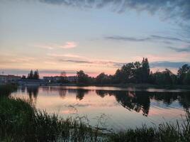 An evening lake in the park reflecting the pink-blue sky on the surface photo