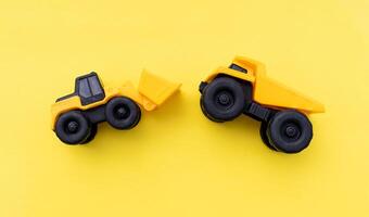 Miniature wheel loader and dump truck isolated on yellow background. After some edits. photo