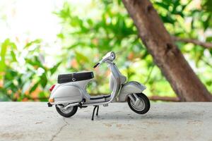 Miniature classic scooter on the cement floor with nature background. After some edits. photo