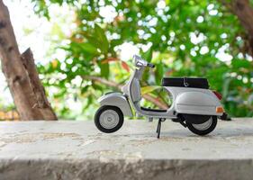 miniatura clásico scooter en el cemento piso con naturaleza antecedentes. después algunos ediciones foto