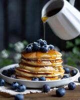 AI generated Gluten free vegan blueberry pancakes, blueberries on top of pancakes and around, The cup is watering the pancakes from above photo