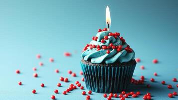 AI generated Blue cupcake with red sprinkles and lit candle on a blue background. photo