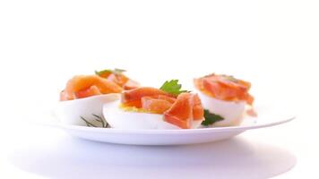 halves of boiled eggs with pieces of salted salmon isolated on white background video