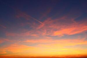 airplane and its trail in the sky. clouds and different color tones in the sky at sunset. Amazing and incredible sunset. photo