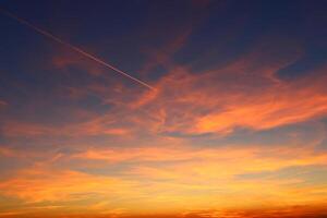 airplane and its trail in the sky. clouds and different color tones in the sky at sunset. Amazing and incredible sunset. photo