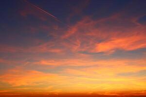 airplane and its trail in the sky. clouds and different color tones in the sky at sunset. Amazing and incredible sunset. photo