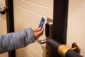 Close-up of a hand holding a key card to unlock a hotel door photo