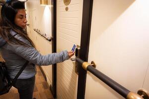 un latín mujer es utilizando un llave tarjeta a desbloquear un hotel habitación puerta foto