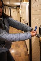 un latín mujer en un corredor participación un llave tarjeta a un puerta bloquear foto