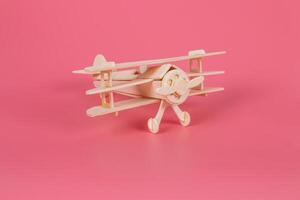 Wooden airplane toy on a pastel pink background photo