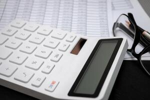 Financial documents and white calculators on black wooden desks photo
