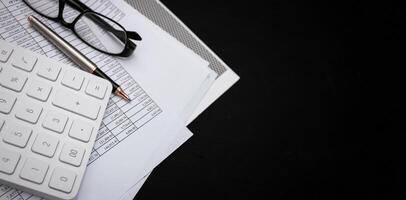 Financial documents and white calculators on black wooden desks photo