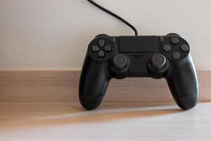 A black joystick for playing games on a wooden table. photo