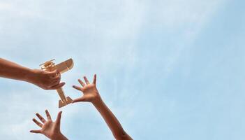 Child Holding a Wooden Airplane Model High in the Sky photo