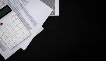 Financial documents and white calculators on black wooden desks photo