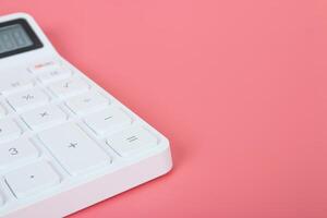 White calculator on a bright pink background, marketing and financial concepts photo