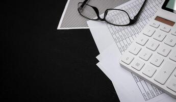 Financial documents and white calculators on black wooden desks photo