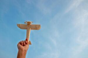 Child Holding a Wooden Airplane Model High in the Sky photo