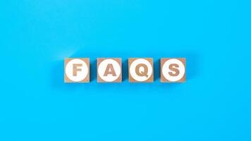 Wooden block cubes for FAQS wording on blue background photo