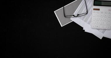 Financial documents and white calculators on black wooden desks photo