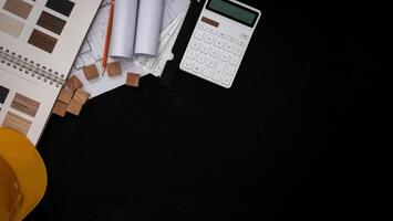 The architect designed the building in the design office, the floor plan with catalogs decorative materials and other accessories on the black wooden table. photo