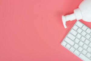 Flat lay, top view office table desk. Workspace with keyboard and hand Sanitizer on pink background. photo