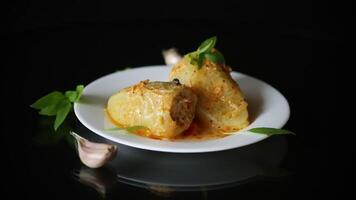 stewed peppers in gravy stuffed with meat and rice in a plate on black background video