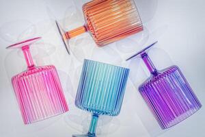 Multi Colored Wine Glasses Laying on a White Surface with Shadows photo