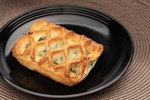 Baked Spinich and Cheese Pastry on a Black Plate photo