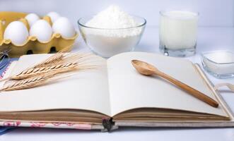 Blank cook book and baking ingredients flour, eggs, milk and sugar. Cooking process. Close-up. photo