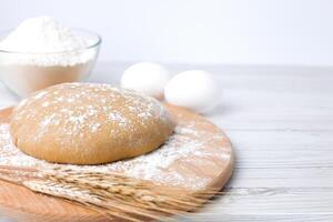 Dough and ingredients for its preparation flour and eggs on white wooden background. Close-up. Copy space. photo