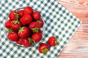 Fresh ripe strawberry in glass bowl on on a on a checkered napkin. Copy space. Close-up. photo