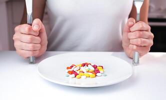 Many multicolored pills lie on a white plate on the table. Healthy food concept. Taking vitamins and supplements. Close-up. photo