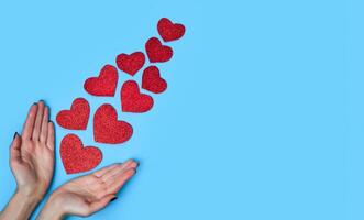 Womans hands near shiny hearts on on blue background. Falling in love concept. Flatlay. Top view. Copy space. photo