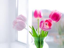 Pink tulips bouquet in glass vase on the window. Springtime. Close-up. photo