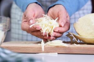 Cooking diet salad, preparation of ingredients. Woman's hands hold chopped cabbage. Close-up. Selective focus. photo