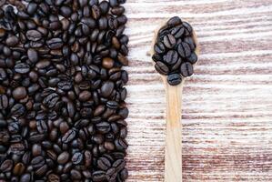 Aromatic coffee beans in a wooden spoon on a wooden table. Banner. Copy space. Selective focus. photo