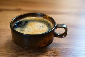 A cup of fragrant fresh coffe on wooden table at cafe. Close-up. Selective focus. photo