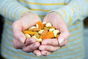 Woman's hands hold a mix of nuts and dried fruits. Healthy food concept. Close-up. Selective focus. photo