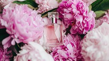 Perfume bottle in flowers, fragrance on blooming background, floral scent and cosmetic product photo