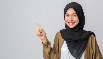 young muslim in hijab pointing one side in studio isolated plain gray background photo