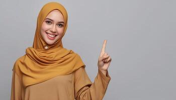 young muslim in hijab pointing one side in studio isolated plain gray background photo